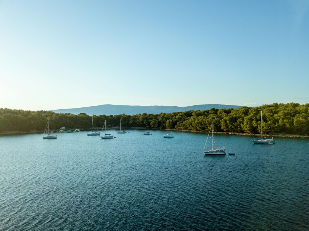 Calm waters with sailboats anchored near Vrboska, Croatia, under a clear sky.